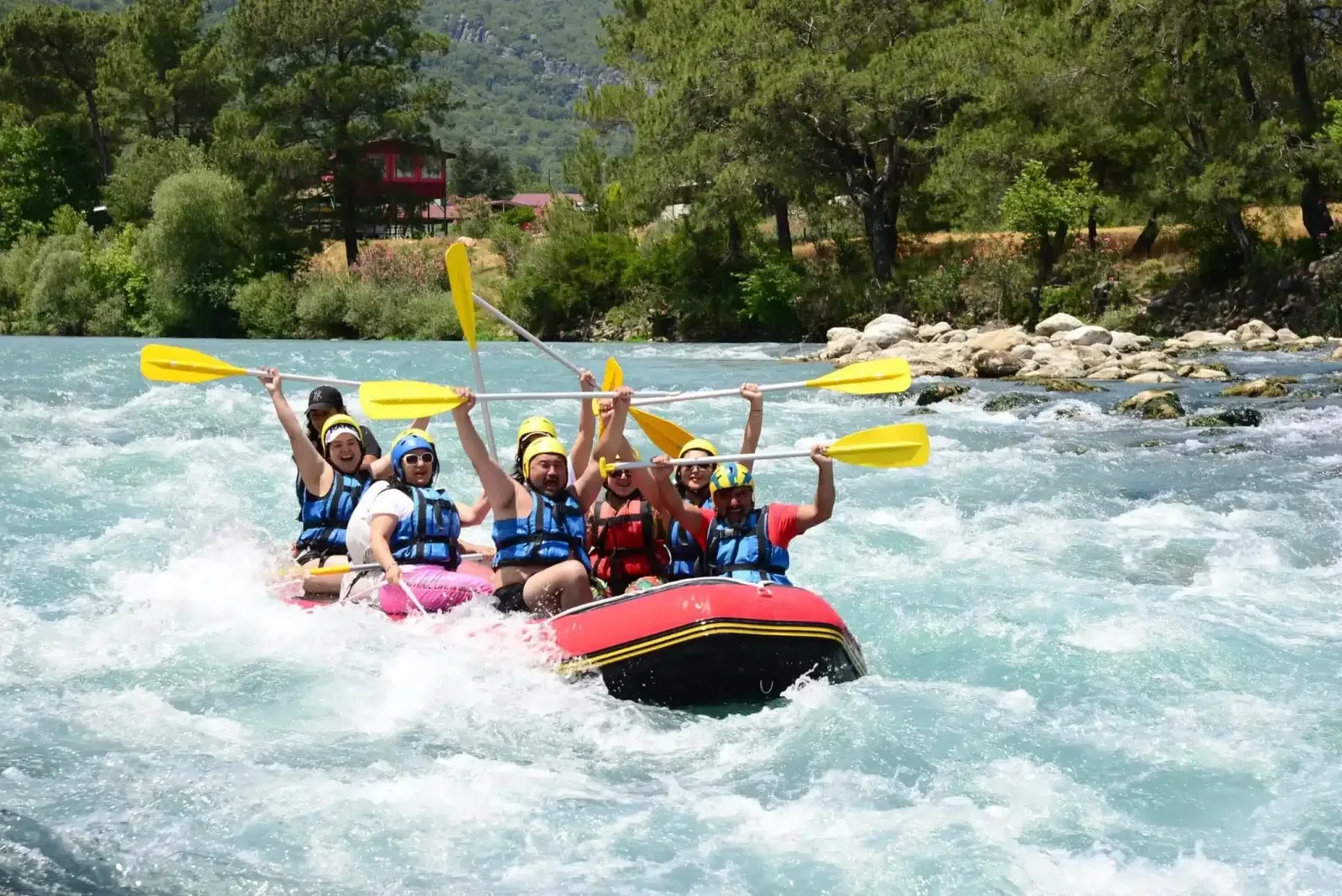 Cheerful rafting group raising their paddles